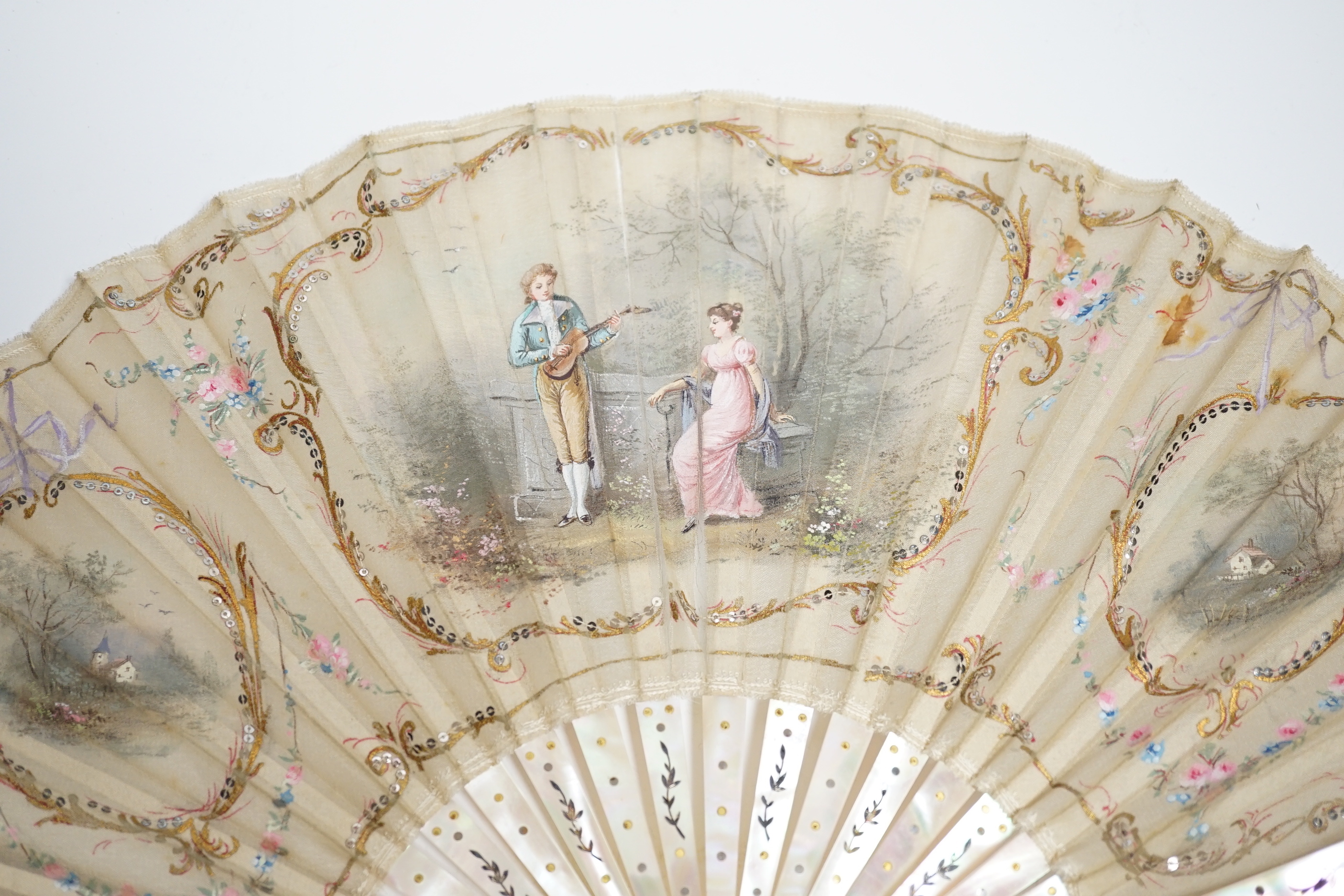 An Edwardian mother of pearl and fine gauze hand painted fan in satin and sequin case
